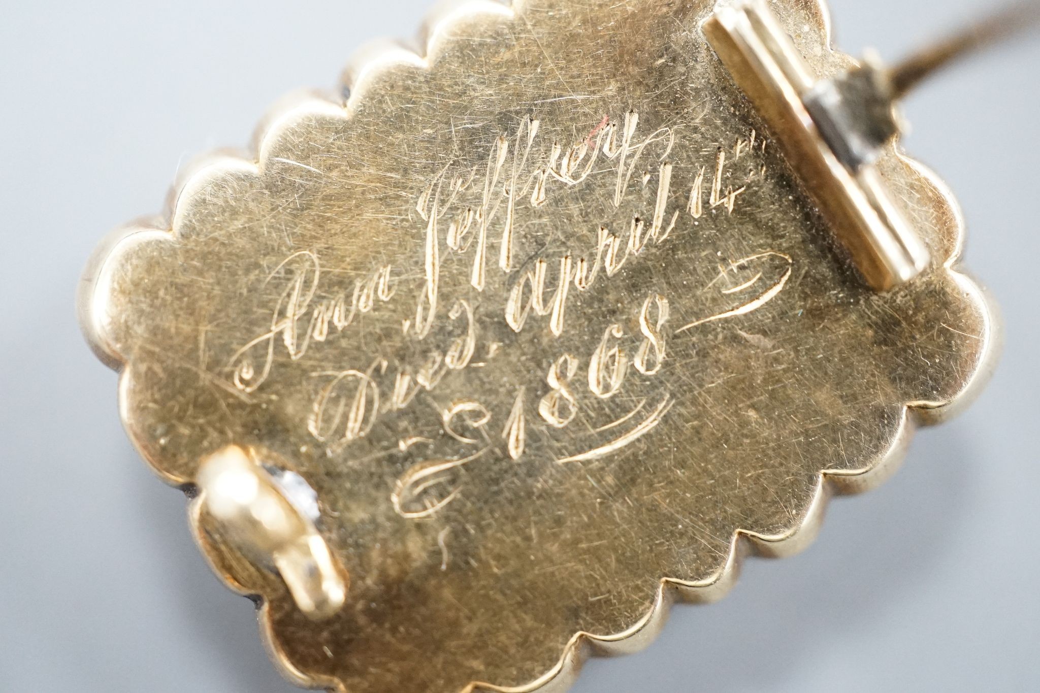 Two 19th century yellwo metal mourning brooches, one with plaited hair, split pearls and engraved inscripotion, the other with sardonyx centre stone, largest 27mm.